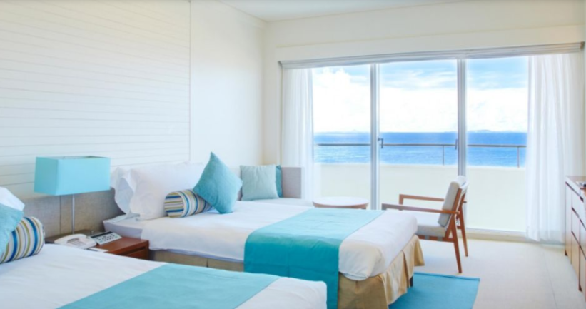 a room with two beds and a window overlooking the ocean