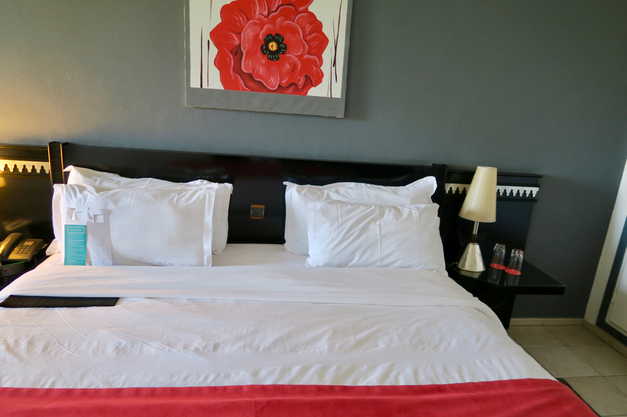 a bed with white sheets and red blanket