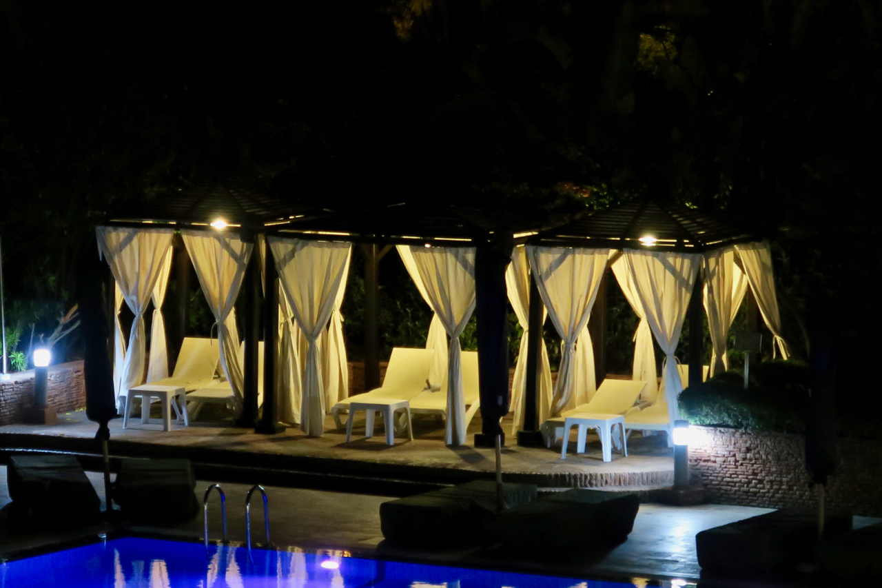 a pool with white chairs and a pool at night