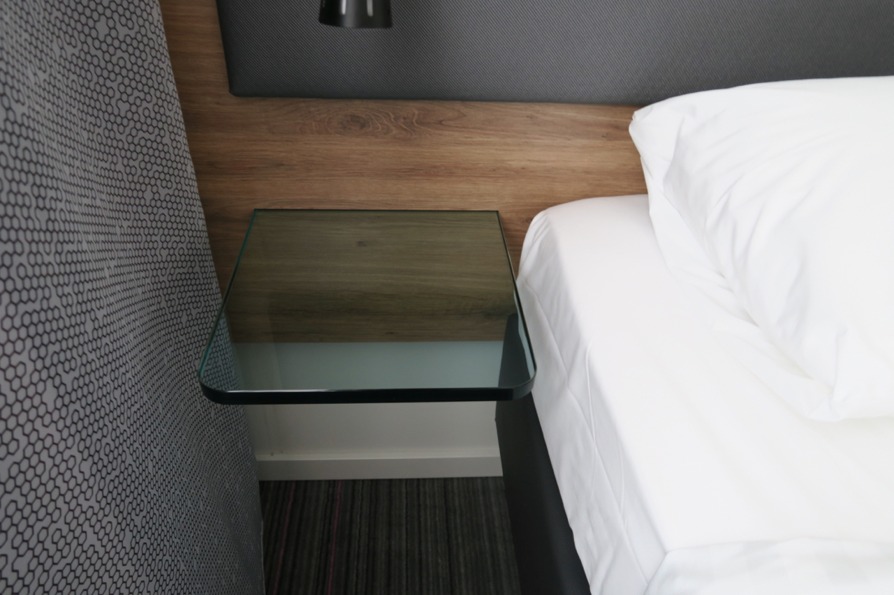 a glass table next to a bed