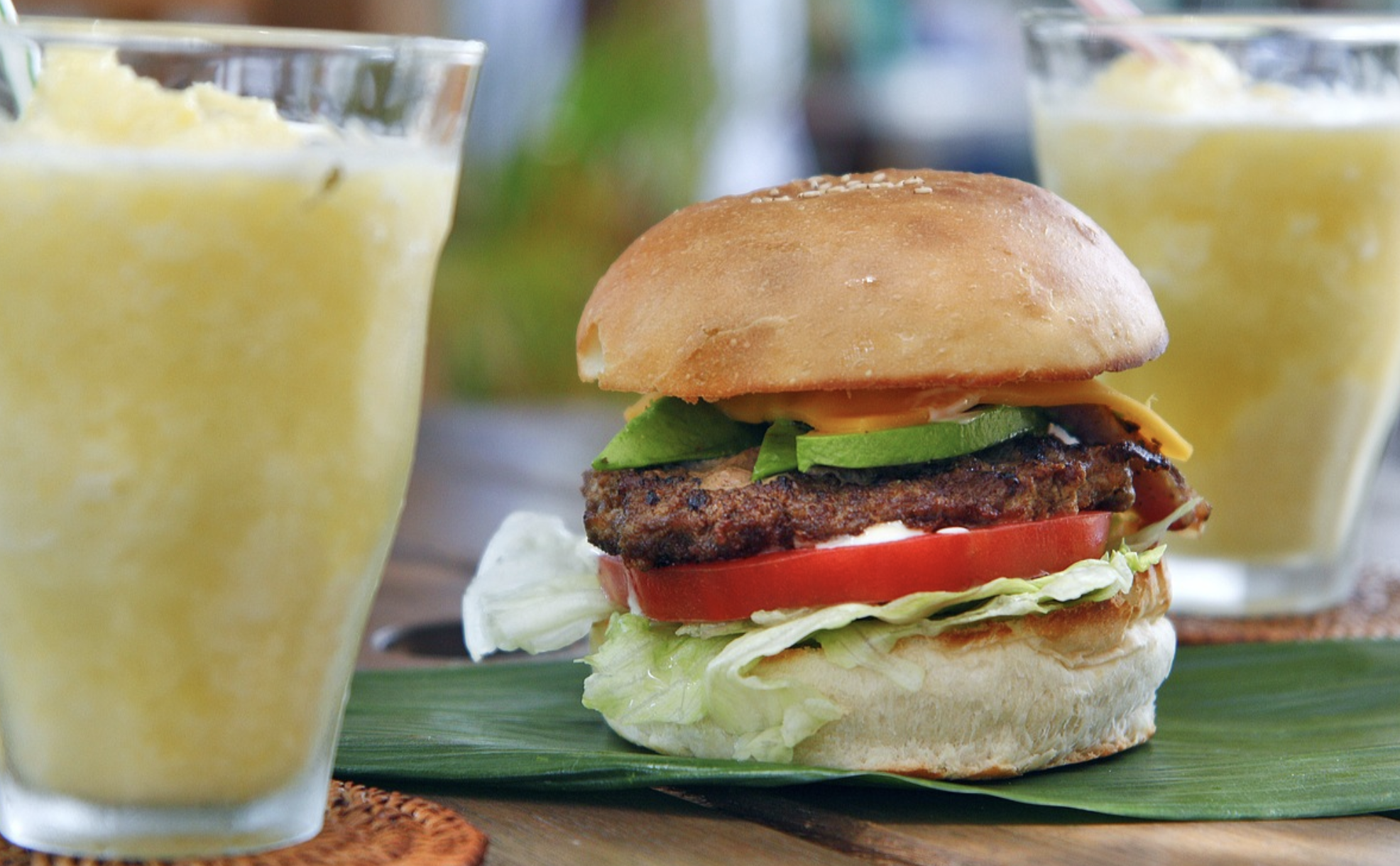 a burger on a leaf next to a drink