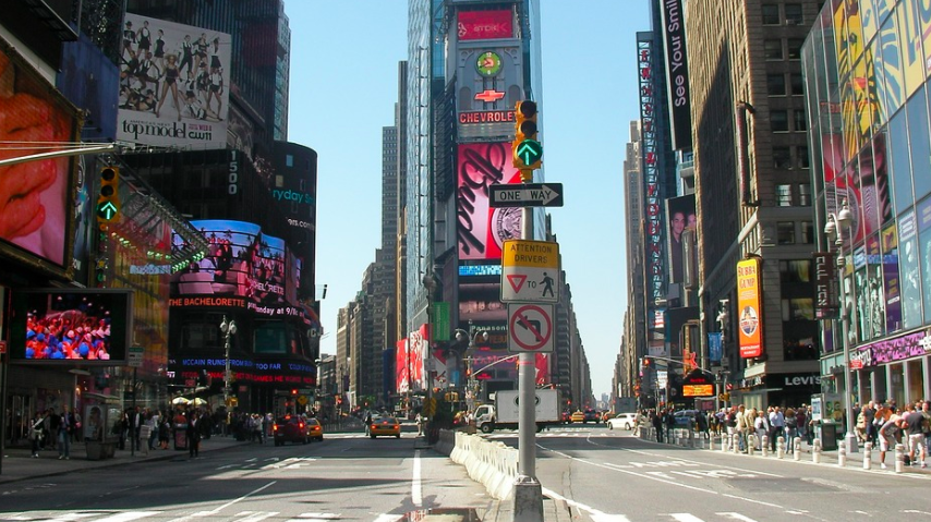 a street with signs on it with Times Square in the background