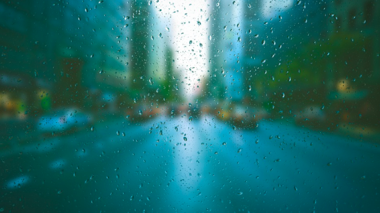 a blurry image of a road with water drops on a window